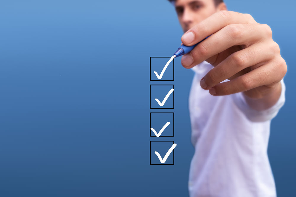 young-man-checking-4-boxes-with-list-options-blue-background